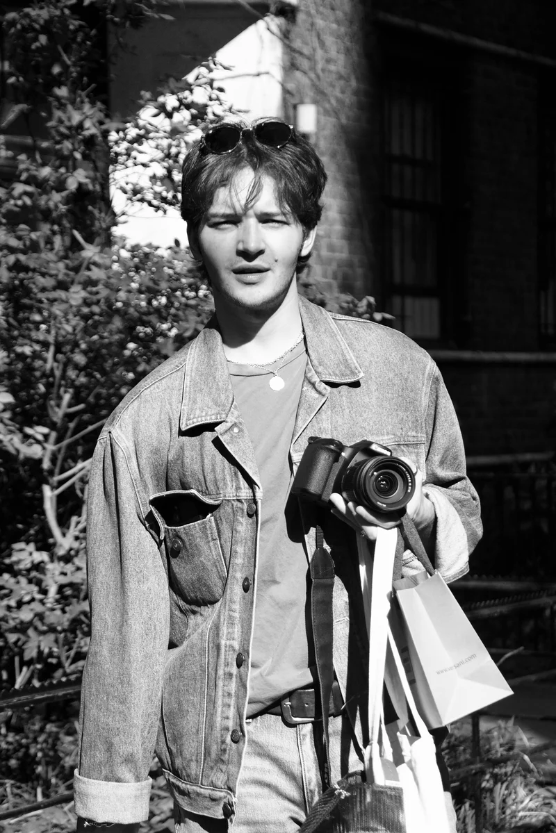 Black and white portrait of Nicholas Shane holding a camera.
